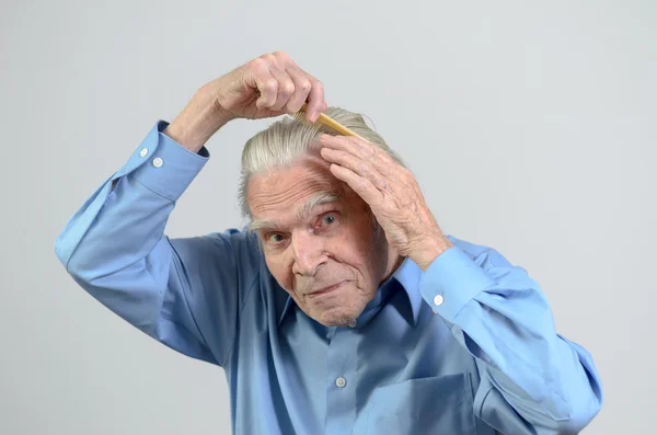 Active elderly man combing his hair with a comb — Stock Photo, Image