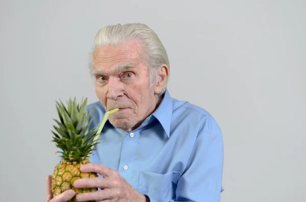 Senior man drinking fresh pineapple juice — Stock Photo, Image