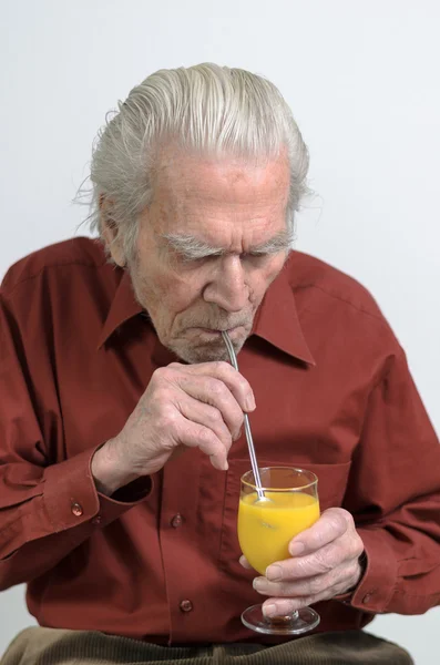 Senior man drinking a glass of orange juice — Stock Photo, Image