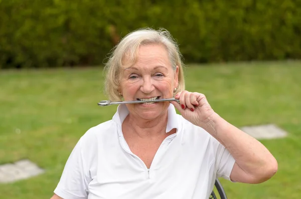 Старшая безмятежная женщина, кусающая гаечный ключ — стоковое фото