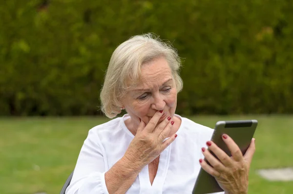 Mulher serena sênior usando um tablet preto PC — Fotografia de Stock