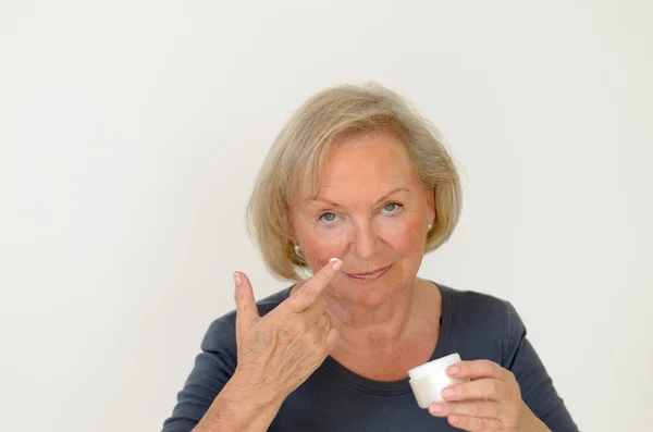 Attractive middle-aged woman applying creme — Stock Photo, Image