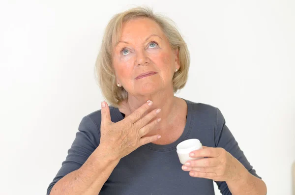 Attractive middle-aged woman applying creme — Stock Photo, Image