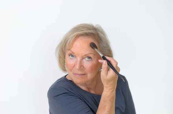 Привлекательная женщина средних лет наносит макияж — стоковое фото