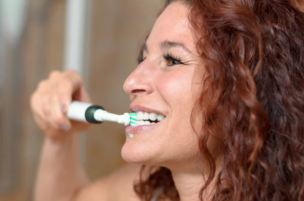 Mujer bonita cepillándose los dientes mientras sonríe — Foto de Stock