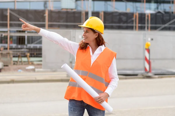 Female construction engineer in vest pointing