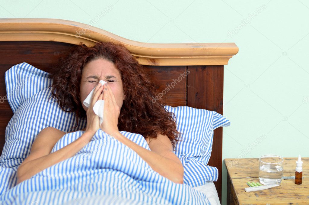 Sick woman blowing nose into tissue