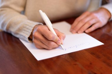 Woman sitting writing on a sheet of white paper clipart