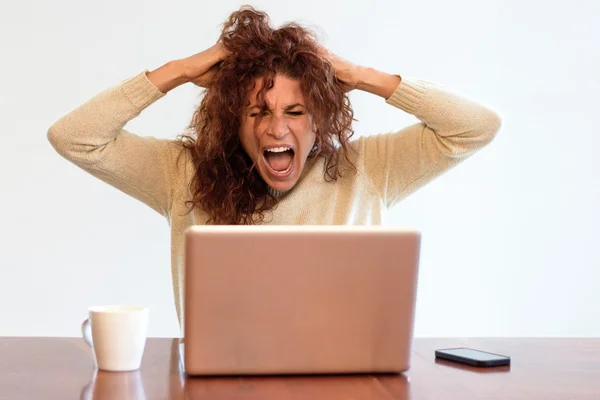 Frustrated businesswoman screaming at her laptop