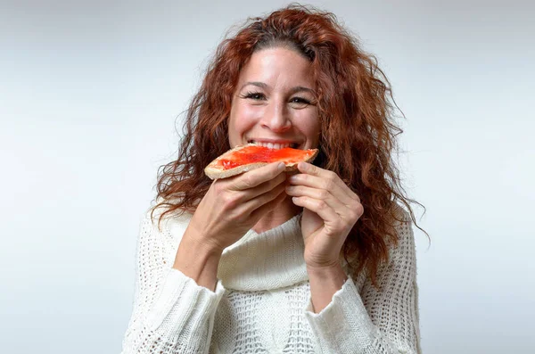 Usmívající se šťastná žena kousání do jam na chleba — Stock fotografie