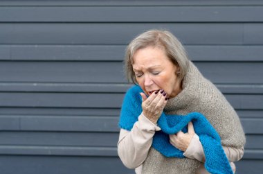 Elegant senior woman coughing into her hand clipart