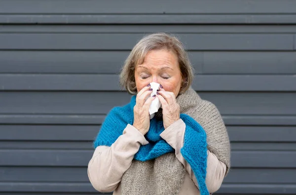 Senior woman blowing her nose on a tissue — Stock Photo, Image