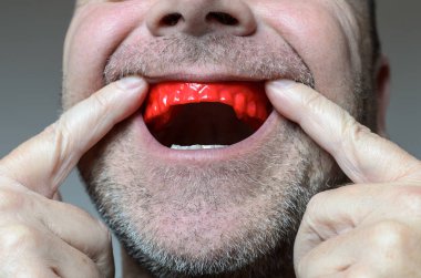 Onun mouthred bir ısırık tabak yerleştirerek adam 