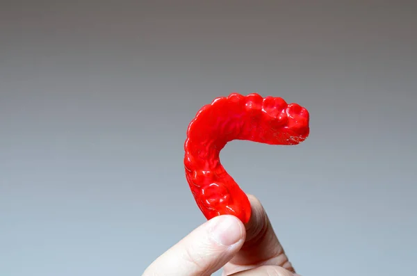 Kırmızı bir ısırık plaka tutan parmak