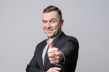 Başparmak ile takım elbiseli sırıtan adam