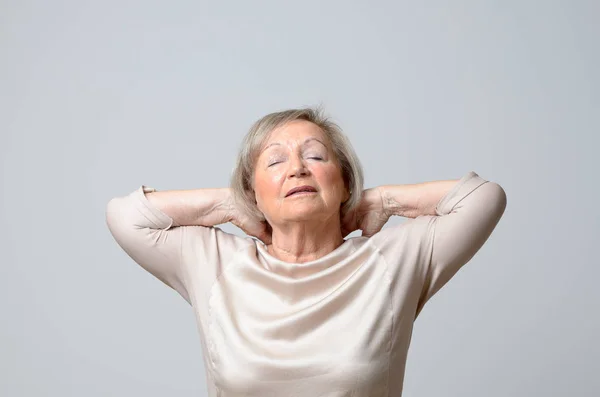 Старшая женщина касается ее шеи — стоковое фото