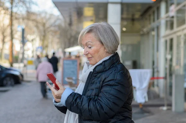 Mujer mayor usando móvil en la calle de la ciudad — Foto de Stock