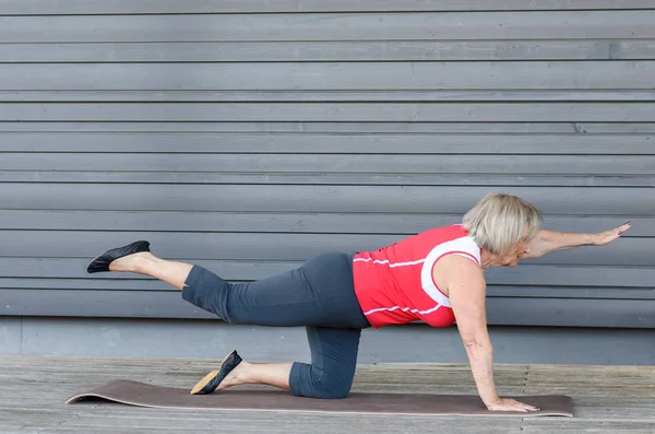 Senior kobieta robi ćwiczenia na macie siłownię — Zdjęcie stockowe
