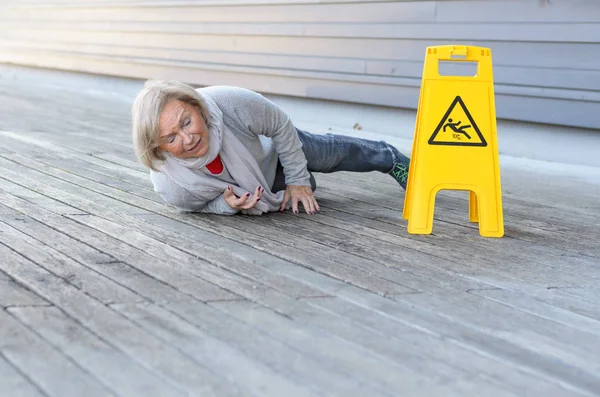Seniorin rutscht aus und stürzt auf nasser Fahrbahn — Stockfoto