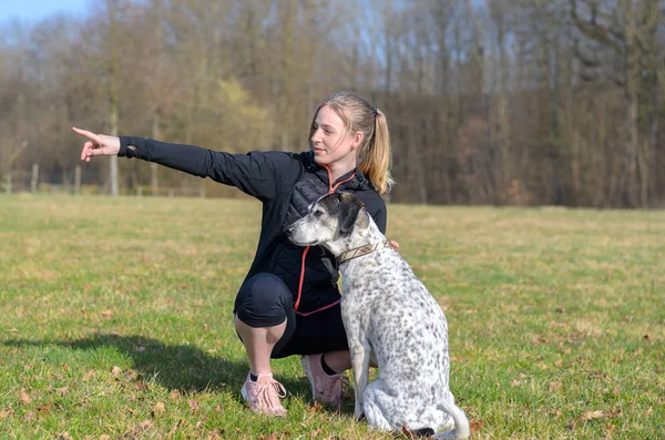 Mulher muito jovem ensinando seus comandos cão — Fotografia de Stock