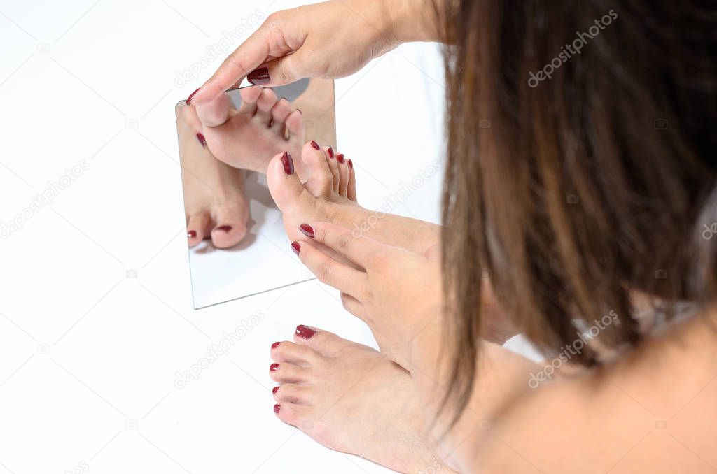 Woman admiring her painted toenails in a mirror