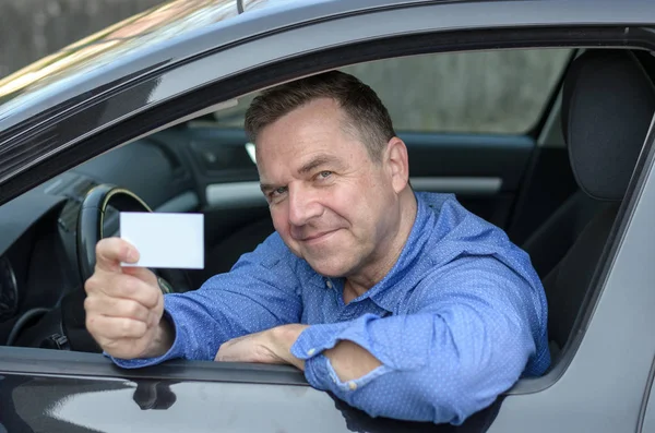 Чоловік середнього віку, що спирається на машину, що показує свою ліцензію — стокове фото