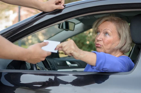 Betrokken bejaarde bestuurder overhandigen aan haar vergunning — Stockfoto