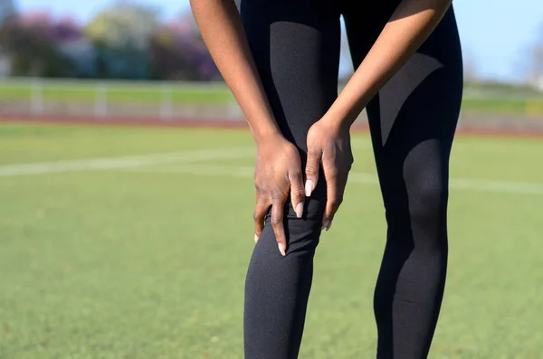 Deportiva musculosa joven mujer agarrando su rodilla — Foto de Stock