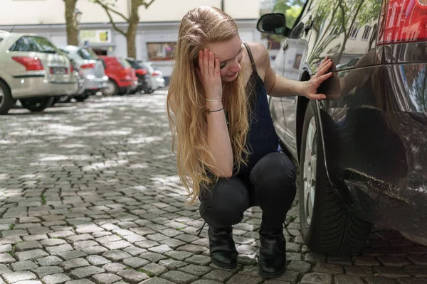 Verzweifelte Frau überprüft den Schaden an ihrem Auto — Stockfoto