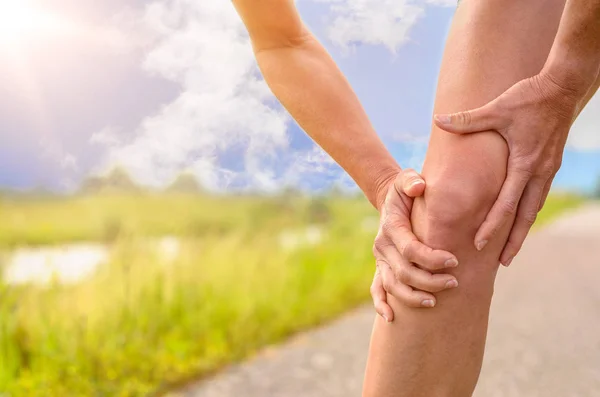 Mujer sosteniendo su rodilla lesionada — Foto de Stock