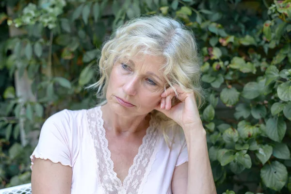 Despondent middle-aged woman sitting thinking — Stock Photo, Image