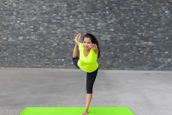 Mujer joven practicando Vrksasana yoga pose — Foto de Stock