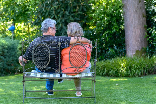 Couple âgé assis sur un banc dans le jardin — Photo