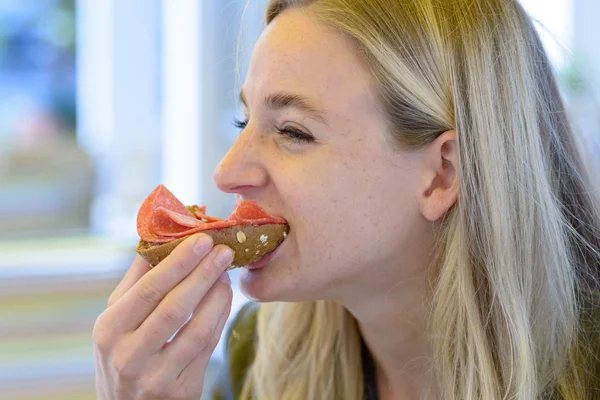 Jovem loira comendo sanduíche — Fotografia de Stock