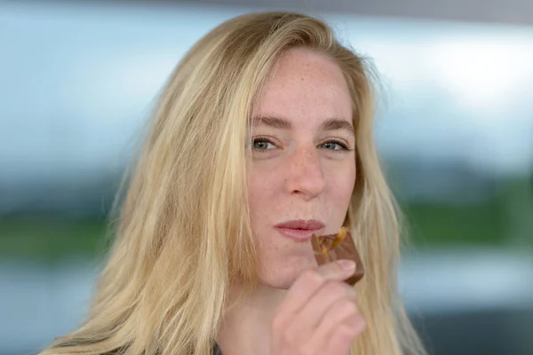 Mujer rubia sonriente comiendo chocolate —  Fotos de Stock