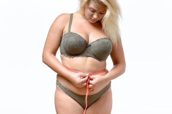 Overweight blonde woman measuring her waist — Stock Image Overweight blonde woman measuring her waist Stock Picture