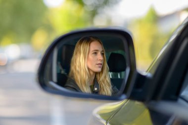 Reflection of blonde woman in car wing mirror