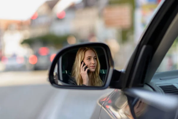 Junge blonde Frau im Außenspiegel eines Autos — Stockfoto