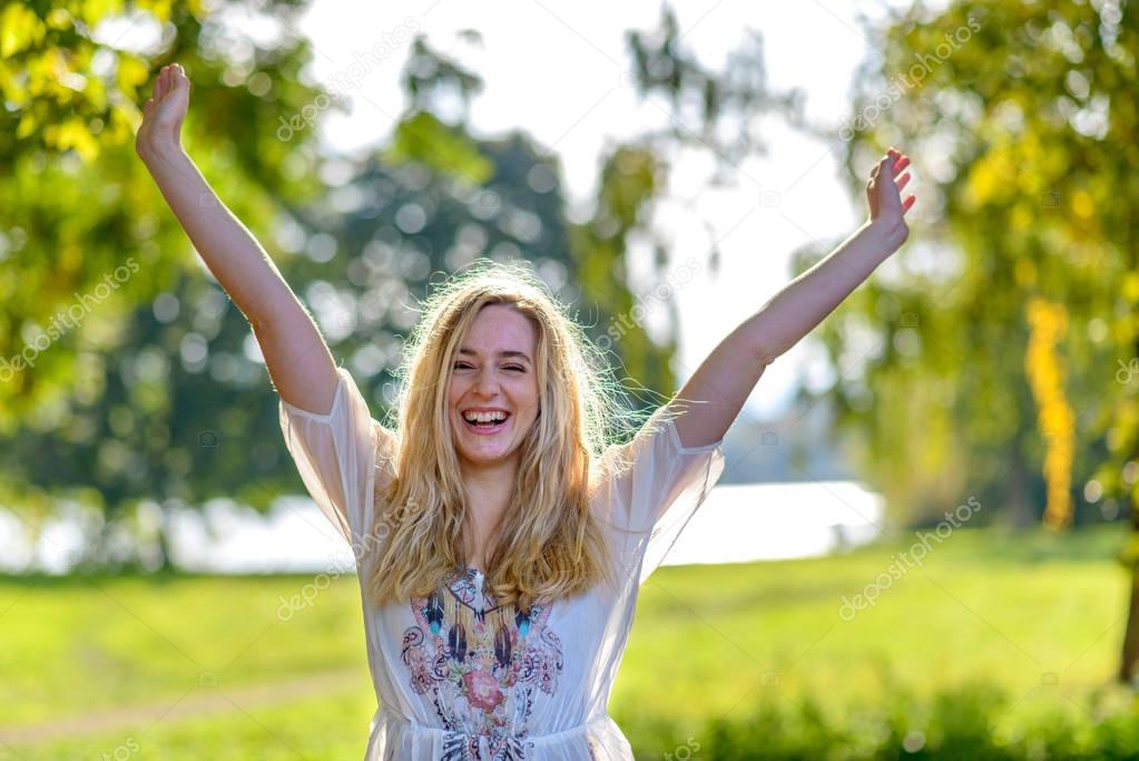 Young happy woman raising hands outdoors
