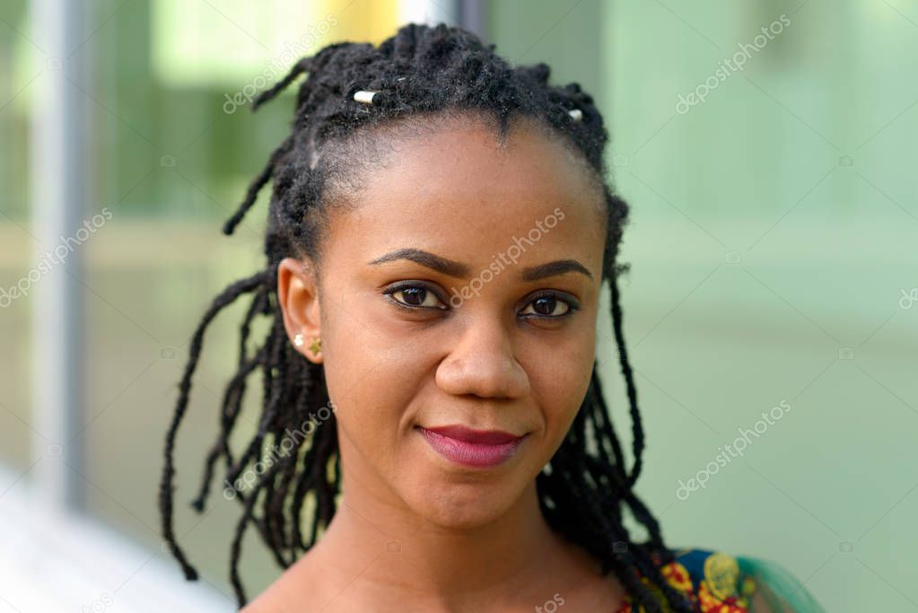 Pretty friendly young African American woman with a braided dreadlock hairstyle in a head and shoulders portrait