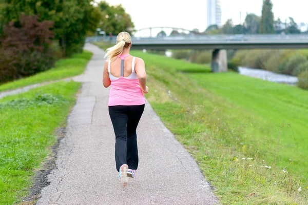 Blonde woman running along river — Stock Image Blonde woman running along river Royalty Free Stock Images