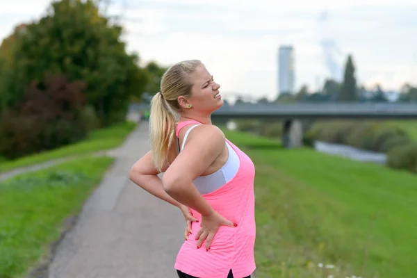 Young blonde woman holding her painful back — Stock Image Young blonde woman holding her painful back Royalty Free Stock Images