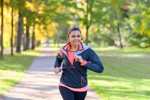 Uśmiechnięta kobieta jogging w parku — Zdjęcie stockowe