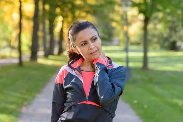 Mujer sosteniendo su doloroso cuello en el parque — Foto de Stock