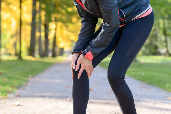 Mujer sosteniendo dolorosa rodilla en parque — Foto de Stock