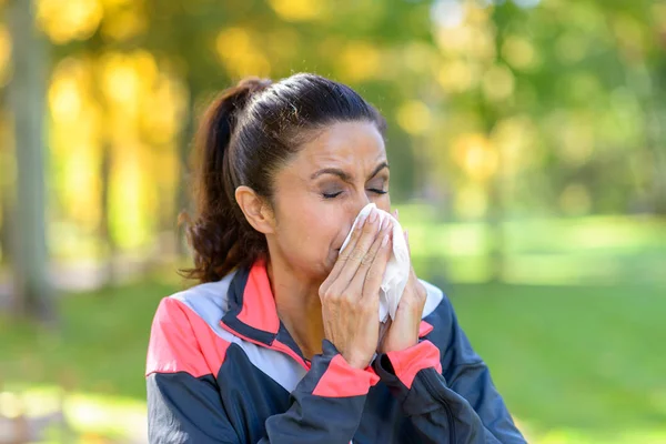 Woman blowing her nose on a tissue outdoors — Stock Photo, Image