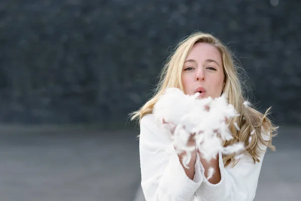 Szórakoztató játékos fiatal nő fúj a fehér tollak — Stock Fotó