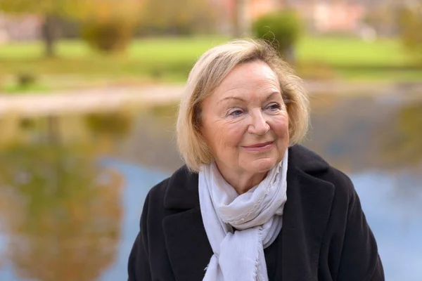 Bejaarde vrouw genieten van een herfstdag buitenshuis — Stockfoto