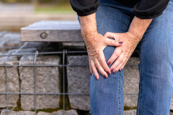 Oudere dame haar knie pijn grijpen — Stockfoto