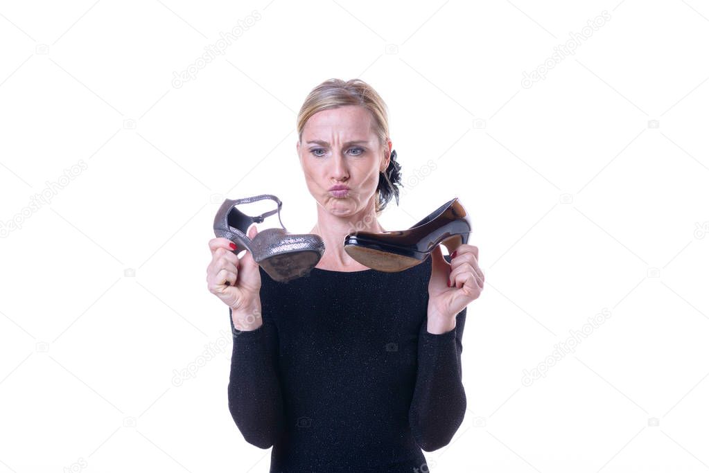 Blonde thoughtful woman holding two shoes